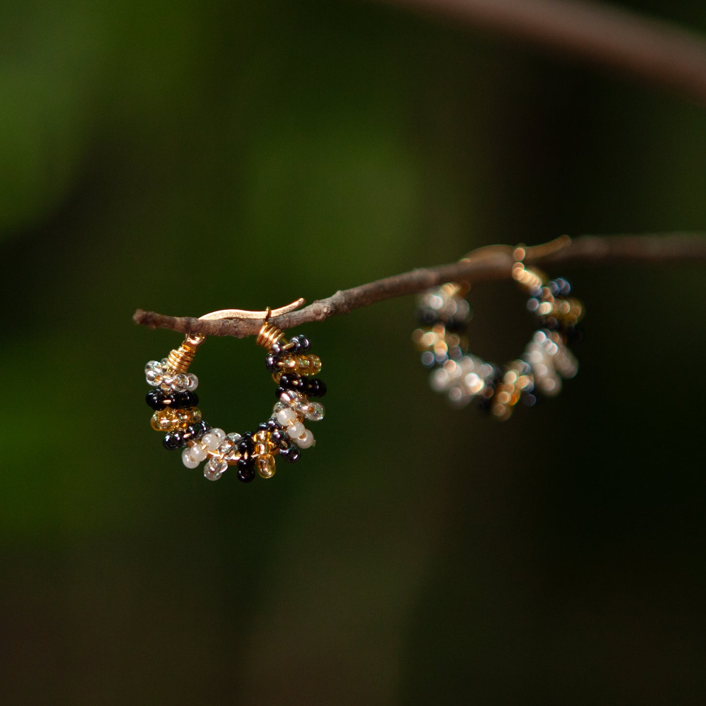 Handmade mini hoop earrings embellished with colorful beads and featuring bronze stud accents and gold plating.