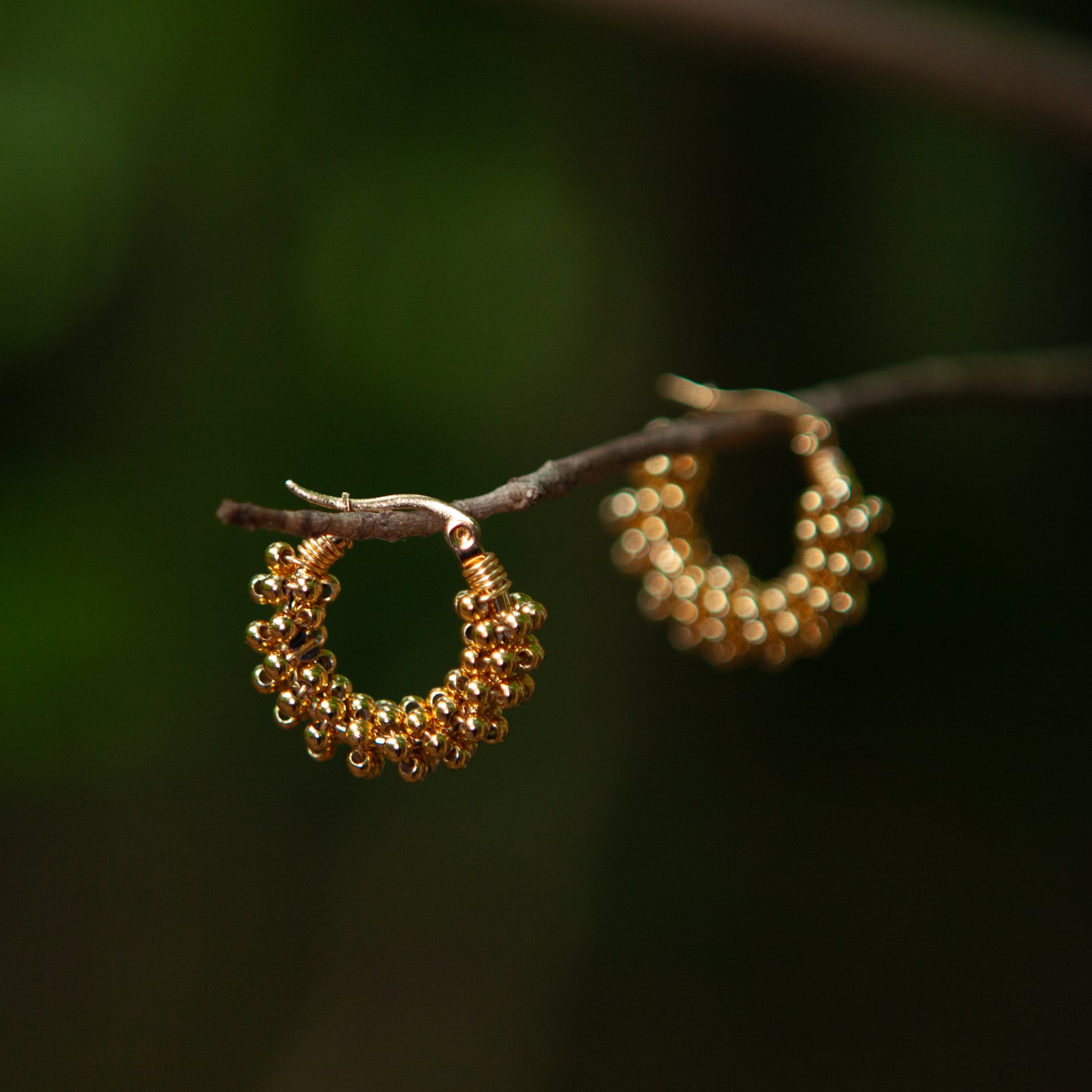 Handmade mini hoop earrings embellished with colorful beads and featuring bronze stud accents and gold plating.