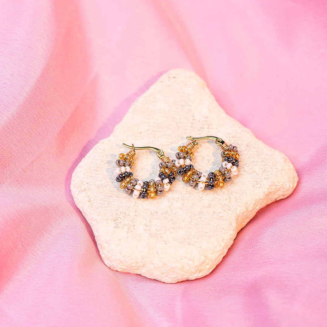 Handmade mini hoop earrings embellished with colorful beads and featuring bronze stud accents and gold plating.