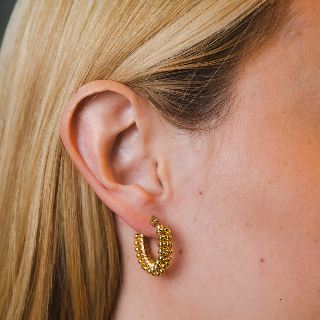 Handmade mini hoop earrings embellished with colorful beads and featuring bronze stud accents and gold plating.